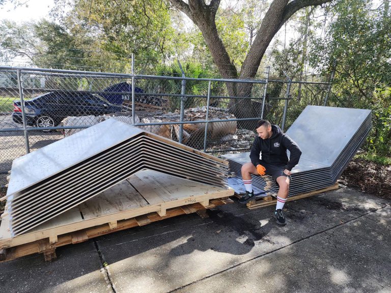 Large angular panels stacked on a pallet outside the workshop