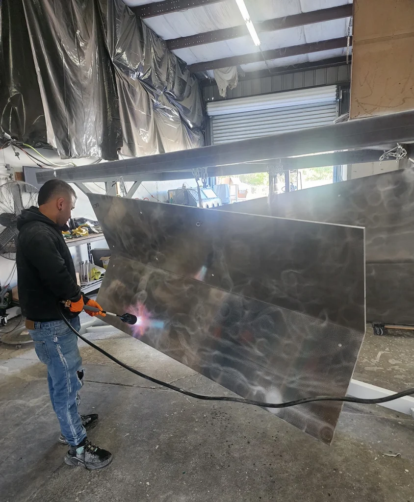 Large metal panel being sprayed in the workshop