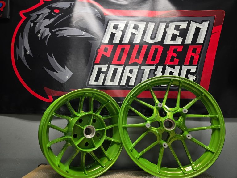 Pair of multi-spoke wheels displayed in front of the Raven banner