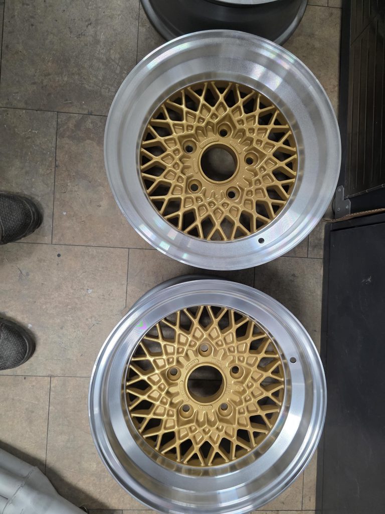 Pair of mesh-spoke wheels leaning against a wall
